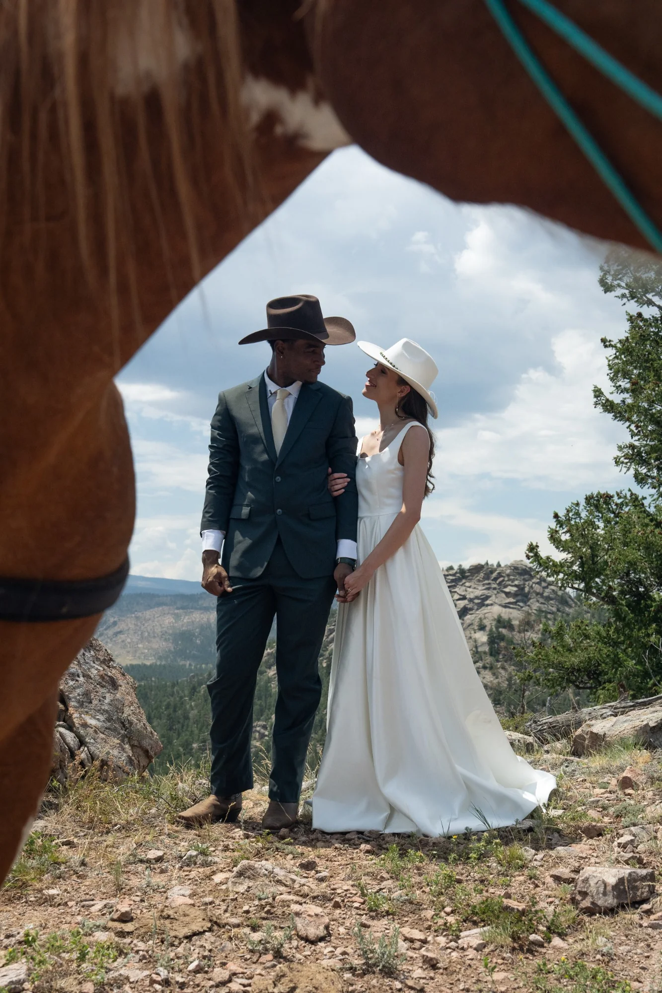 Isabella and Tim at a Colorado mountain overlook framed by a horse during their horseback elopement