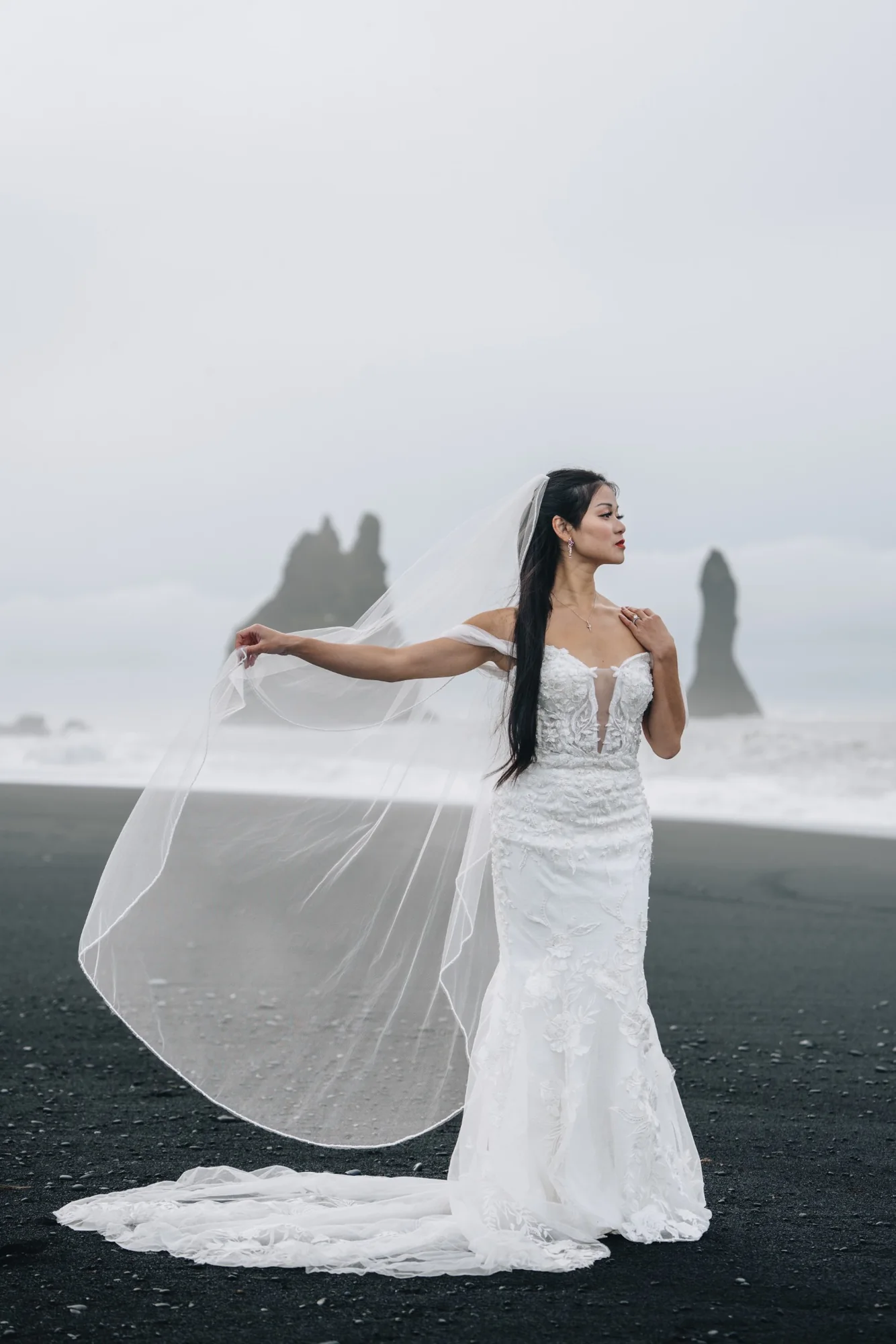 Bride in her wedding dress on Reynisfjara Black Sand Beach with the sea stacks behind her