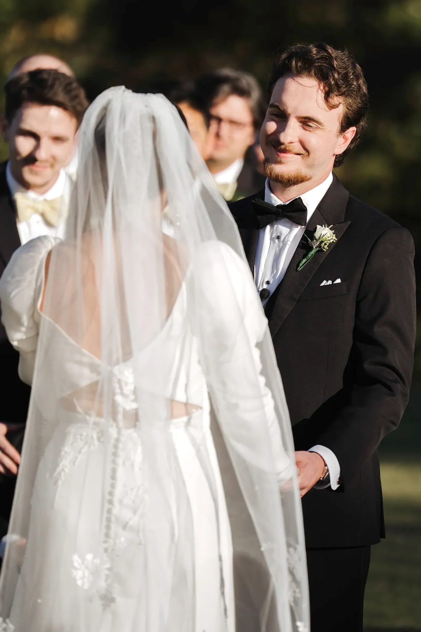 Groom smiling at his bride during an outdoor wedding ceremony